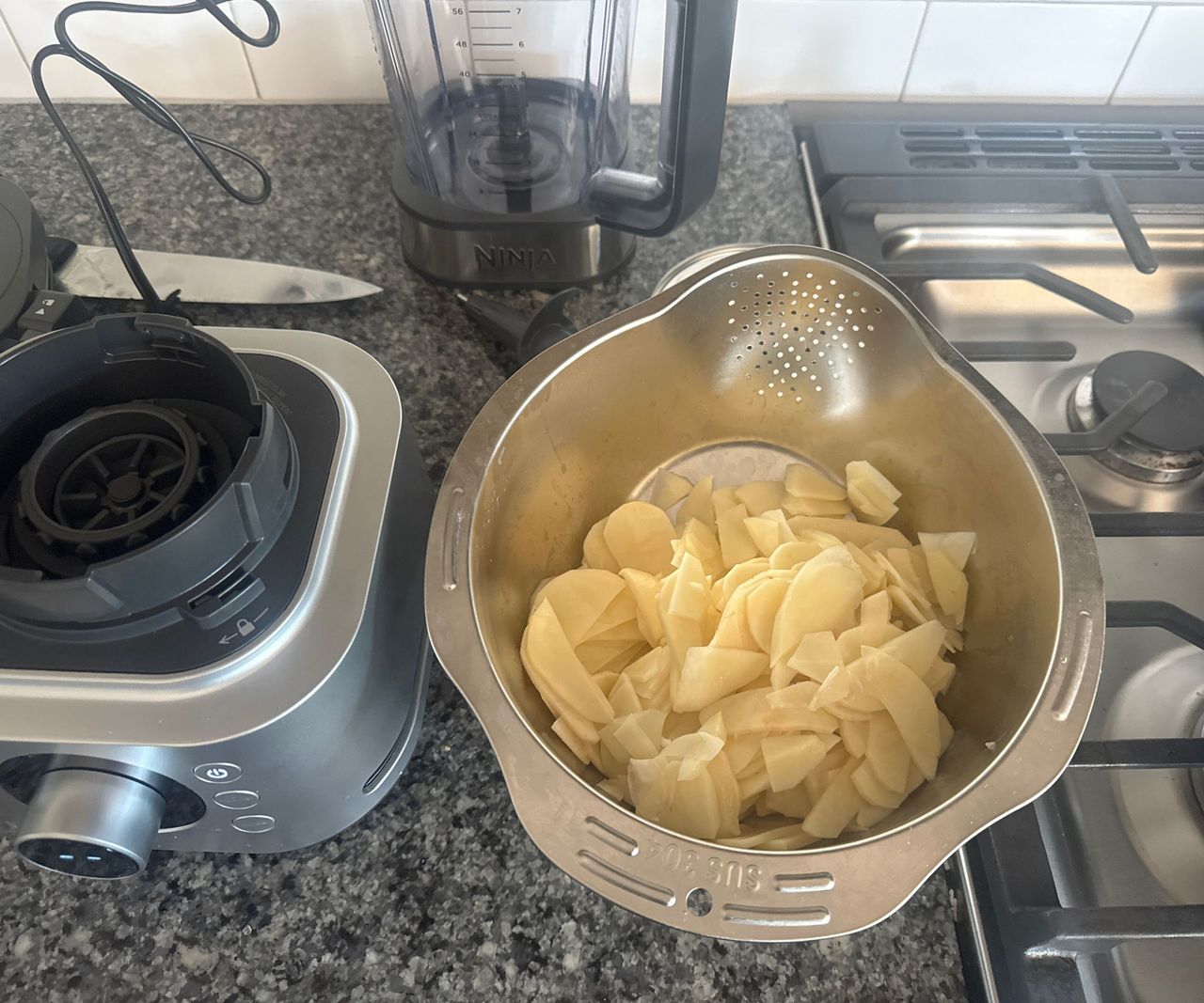 Sliced potato in a stainless steel strainer