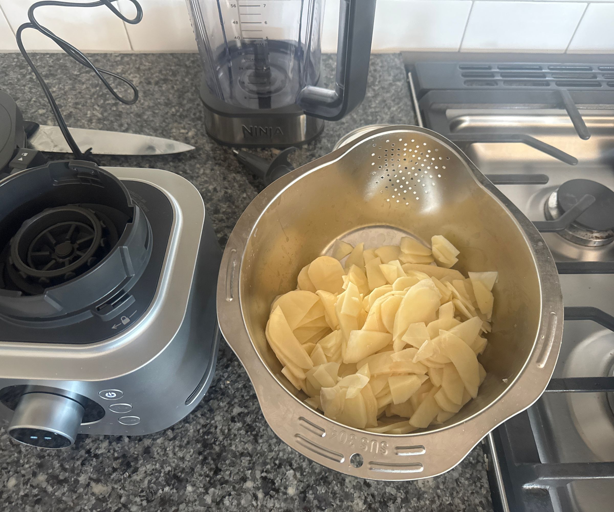 Sliced potato in a stainless steel strainer