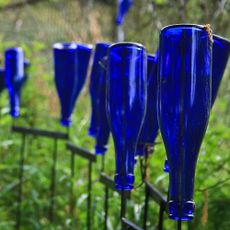 Several blue glass bottles upside down in a garden