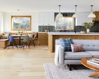 An open plan kitchen, living and dining space, with white oak units and a grey sofa
