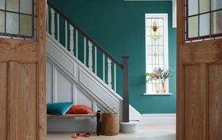 Hallway with green feature wall behind the stairs and a stain glass window