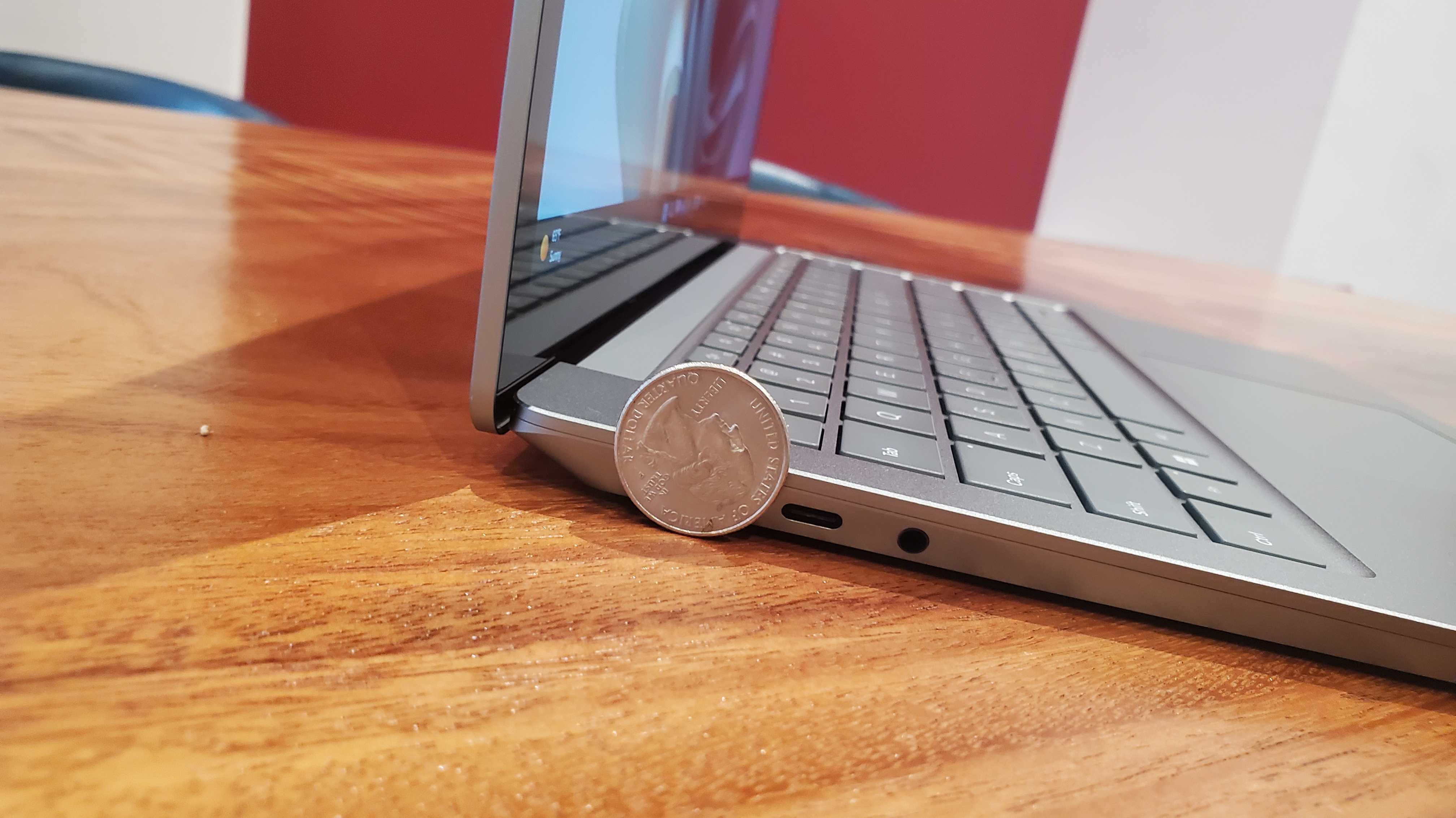 closeup of silver laptop sitting on a wooden desk with a quarter