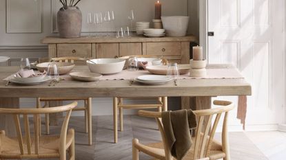 A dining room with wooden table and chairs, and a wooden side board