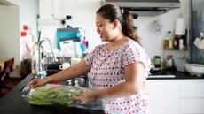 Woman in kitchen removing vegetables from a plastic wrapper