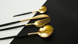 Best flatware sets: a gold and black set on a white and black table