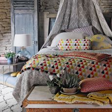 bedroom with wooden bed mattress pillows and brick wall withbcushions