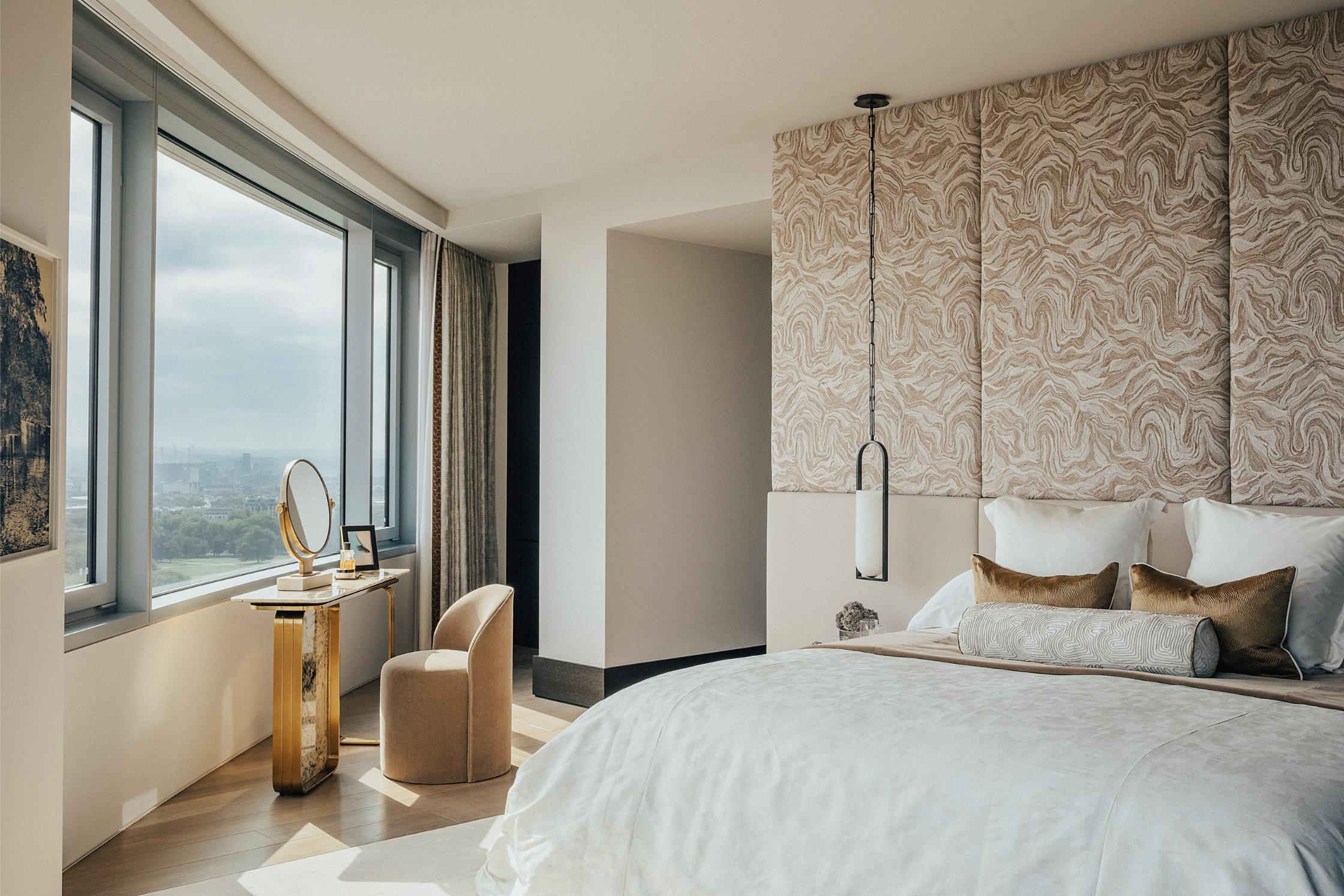 A contemporary bedroom with a curved wall and window, with a dressing table at an angle opposite the bed