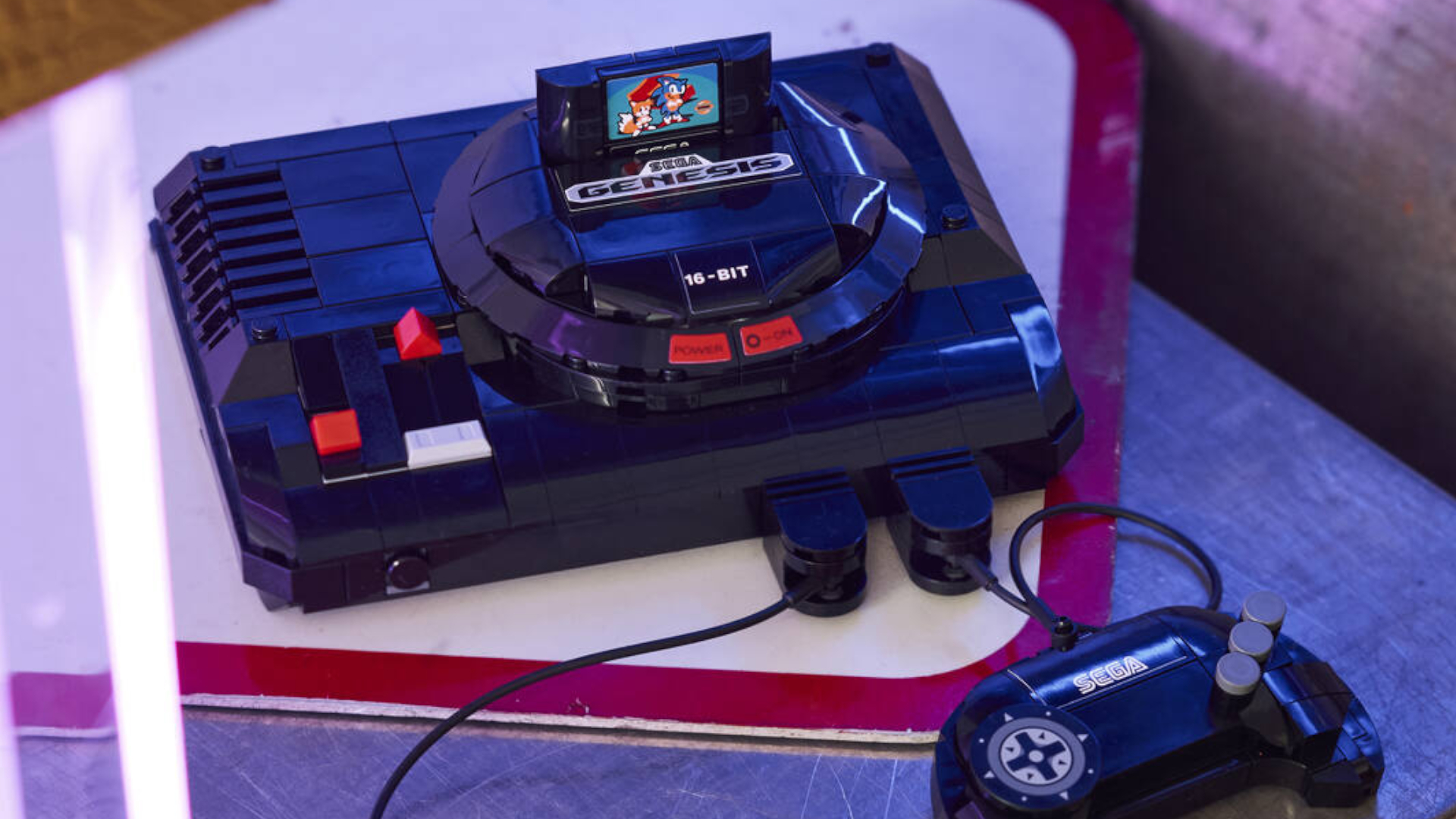 Lego Sega Genesis Console and controller on a mat in a purple-tinged environment