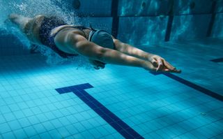 Person swimming underwater in pool