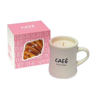 A pink cube shaped box beside a candle in a mug