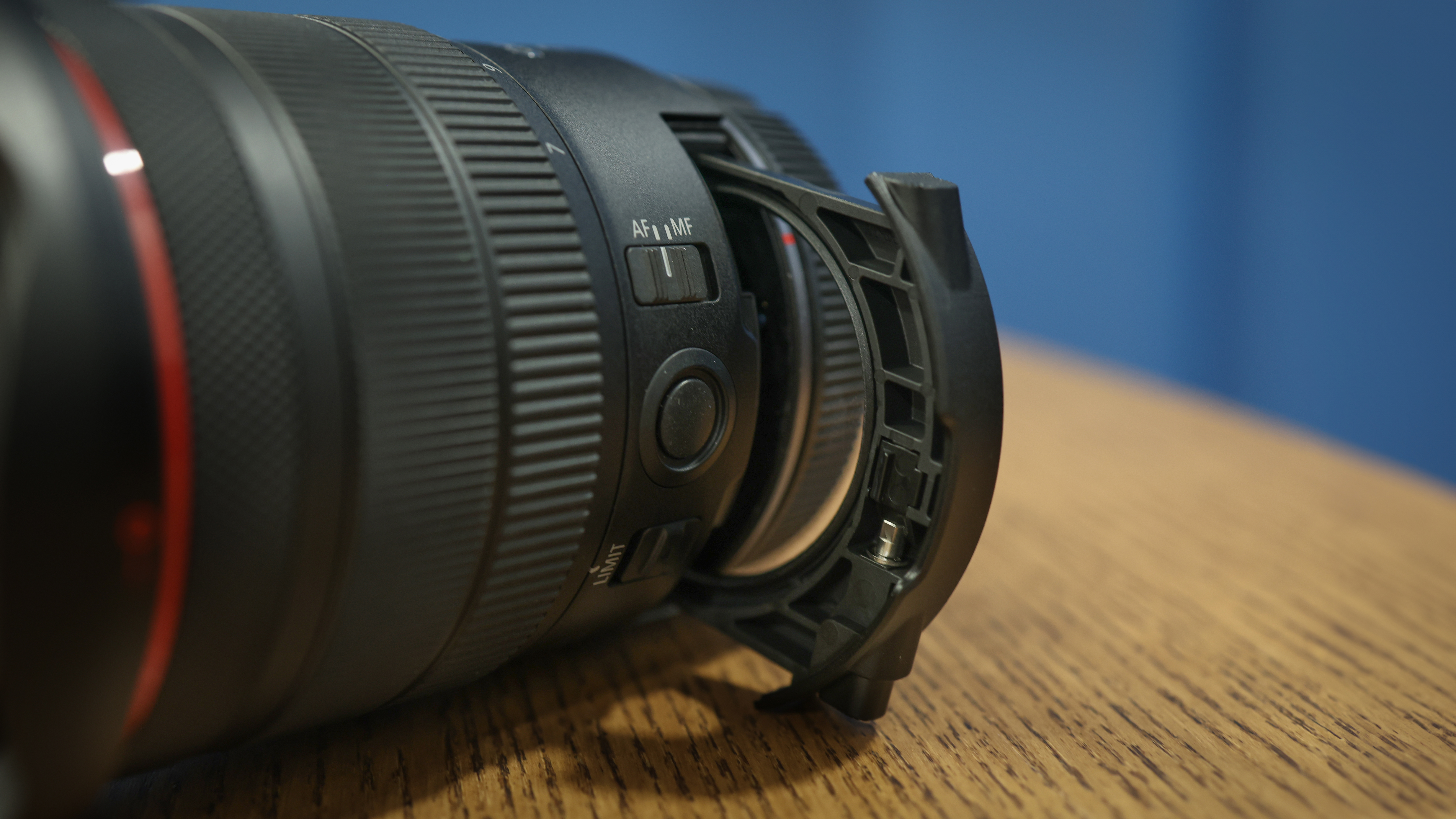 Canon RF 7-14mm f/2.8-3.5L Fisheye STM on a wooden surface in front of a blue background