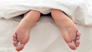 A pair of feet sticking out of the end of a bed