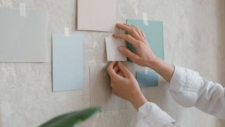 Someone putting small paint samples on a wall