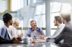 Happy business leader communicating with his team while working a meeting in the office.