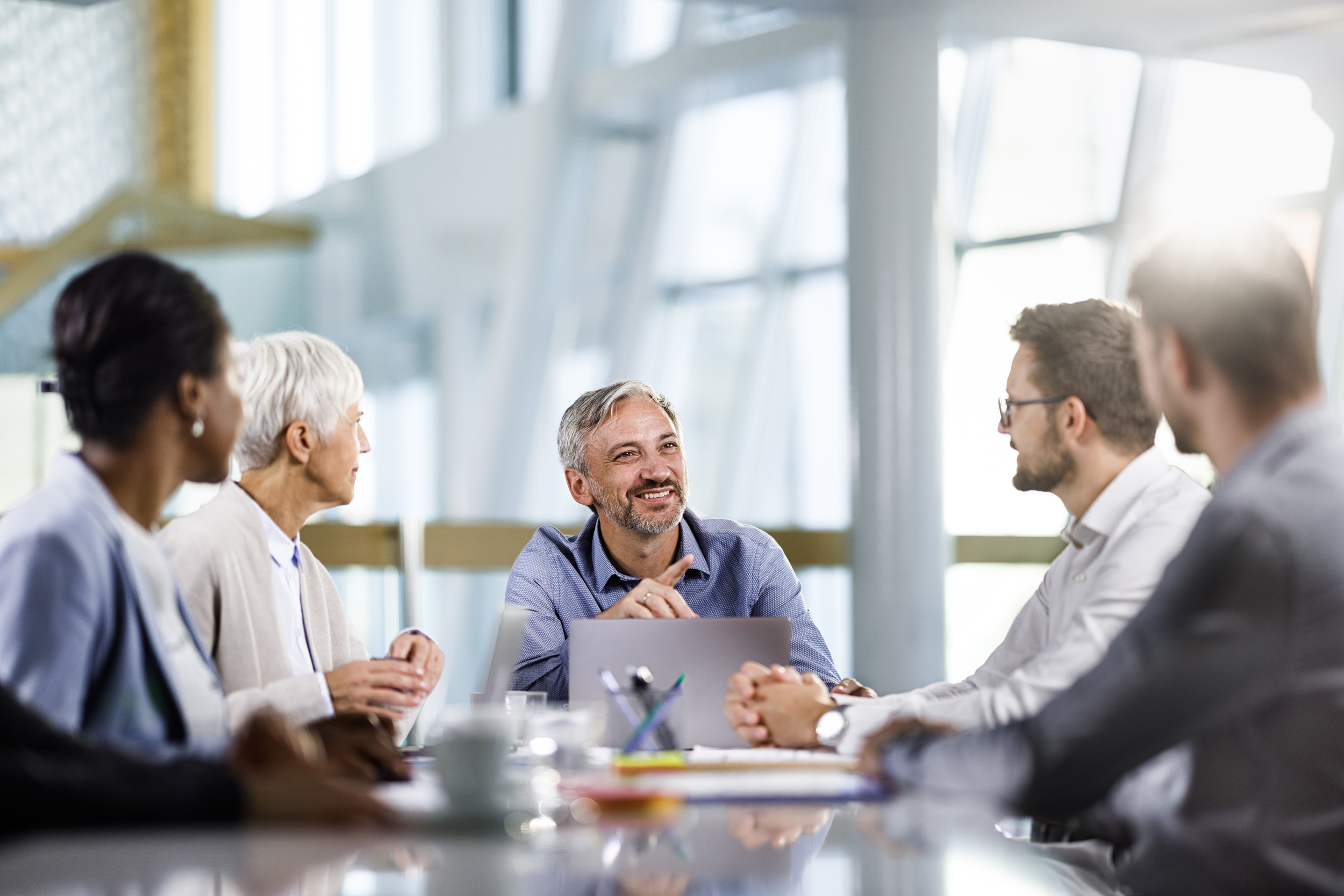 Happy business leader communicating with his team while working a meeting in the office.