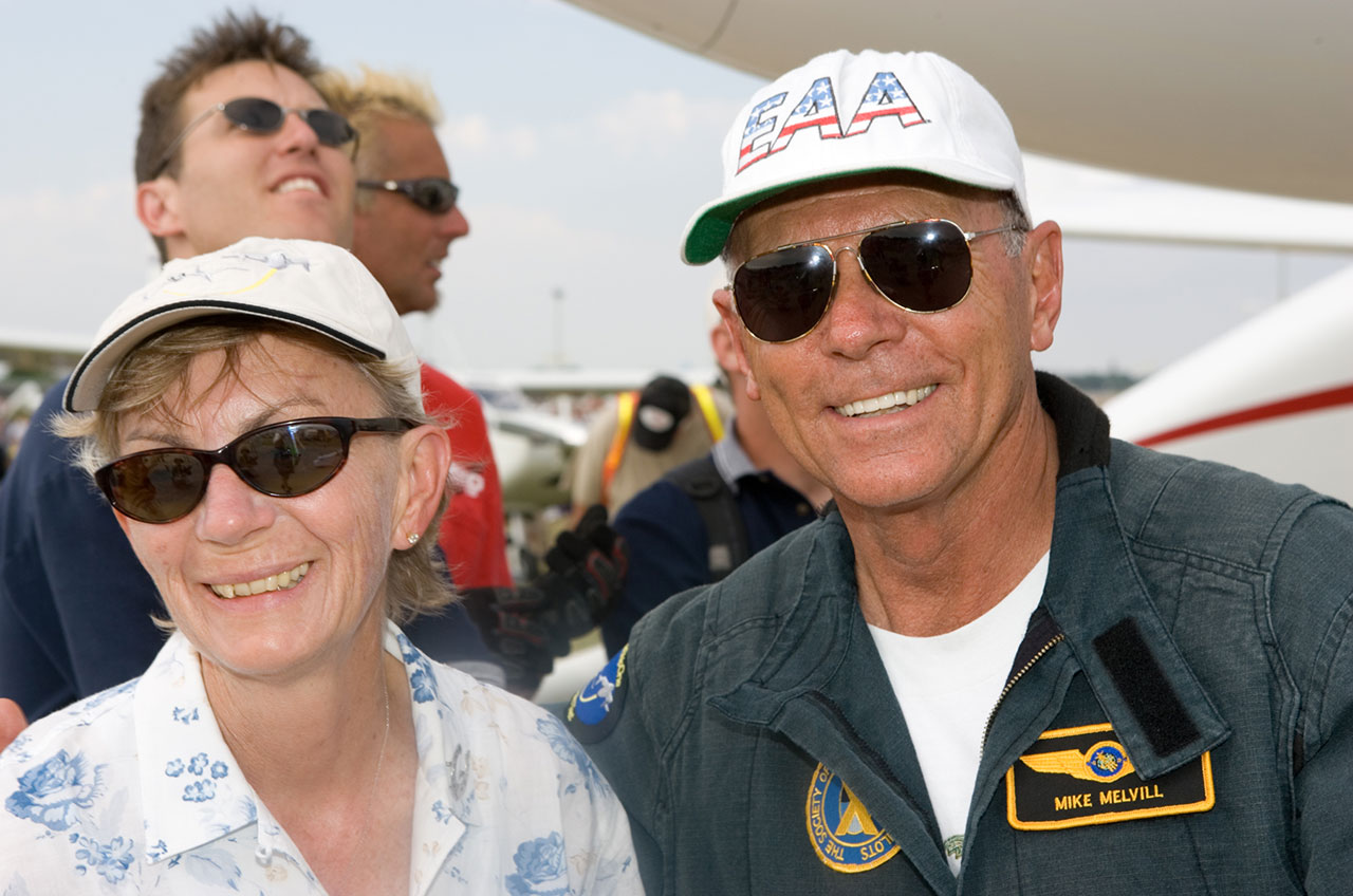 mike and sally melvill, both smiling and wearing hats and sunglasses