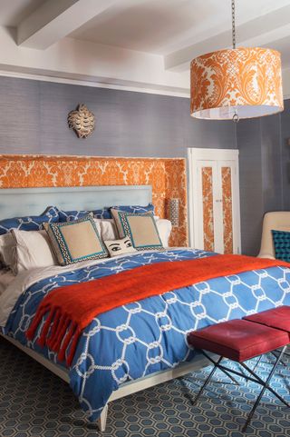 Blue orange and grey bedroom with wallpapered headboard