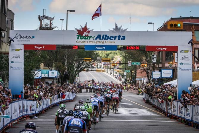 The peloton goes through the finish single file with one lap to go.