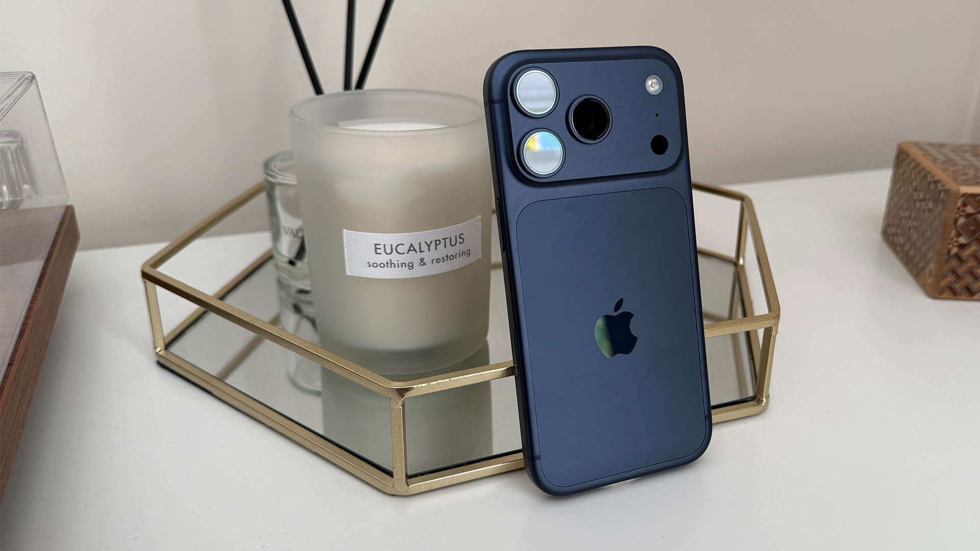 Apple iPhone 17 Pro smartphone leaning in front of candle with rear camera array visible