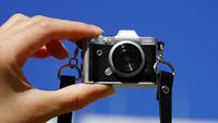 Haru Mini Retro camera being held by fingertips in front of a blue sky