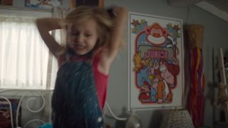 A little girl throwing her goggles in disgust with a Donkey Kong, Jr.poster on the wall behind her.