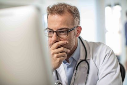 Doctor sitting at desk working on computer 