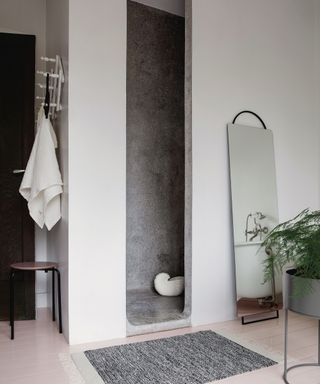 White bathroom with shower in alcove with gray finish and large arched mirror