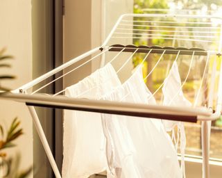 Hanging laundry on balcony on the drying rack opposite sea and palm trees view at sunset sunshine