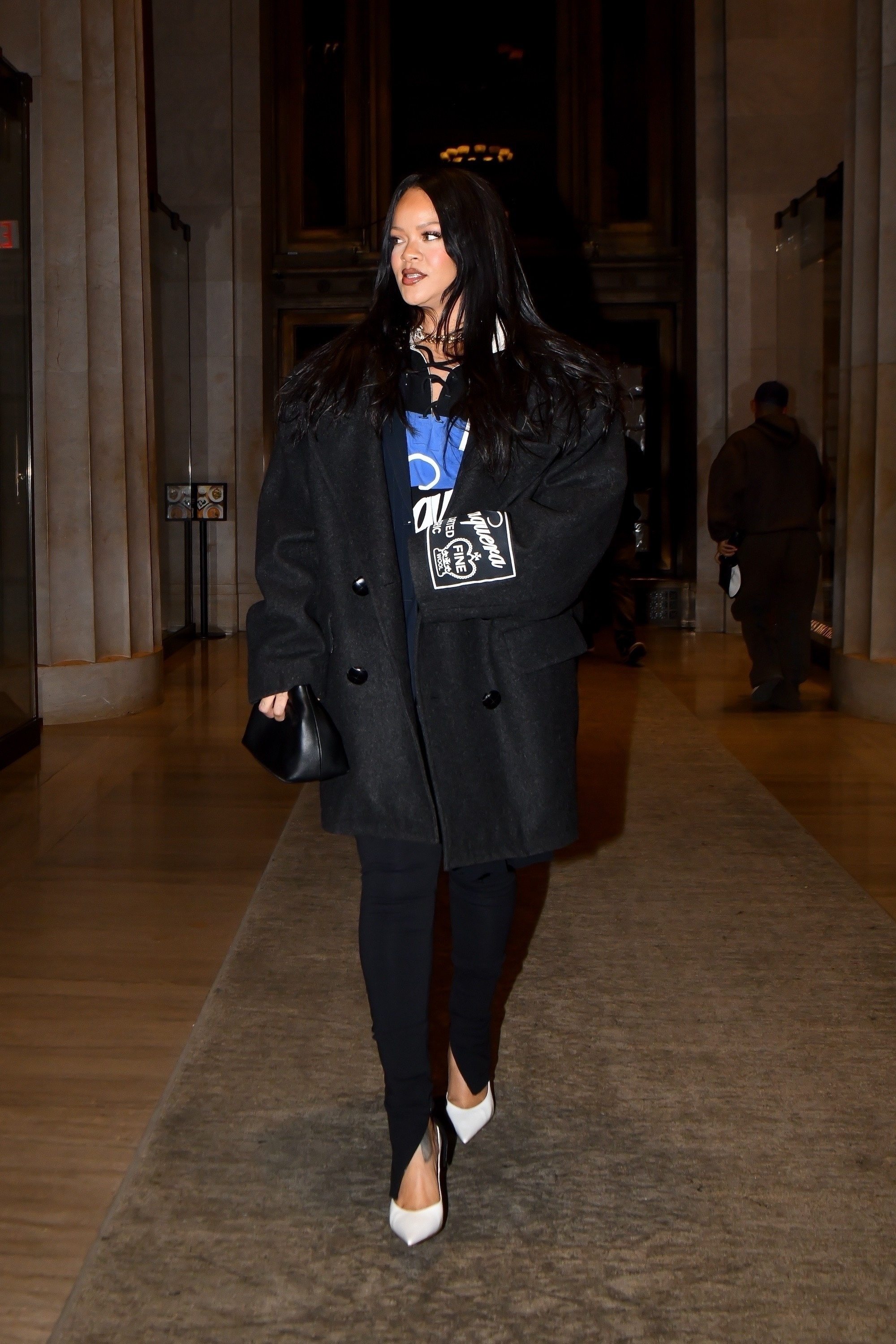 Rihanna wearing white heels with black legging and an oversized double breasted blazer.