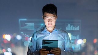 An IT executive looking at a tablet with a hologram of stats floating above it to represent a chief AI officer.