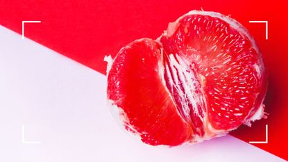 Red tangerine on pale pink and red background to represent female masturbation