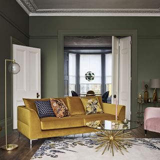 Gold sofa and sputnik coffee table in room with green walls