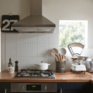 White kitchen with white splashback tiles, a wooden worktop and kitchen accessories