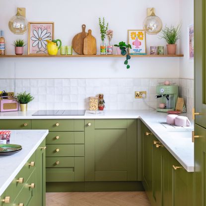 White painted and tiled kitchen with green painted kitchen cabinets and drawers with gold hardware