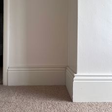 White wall with skirting board by neutral carpet
