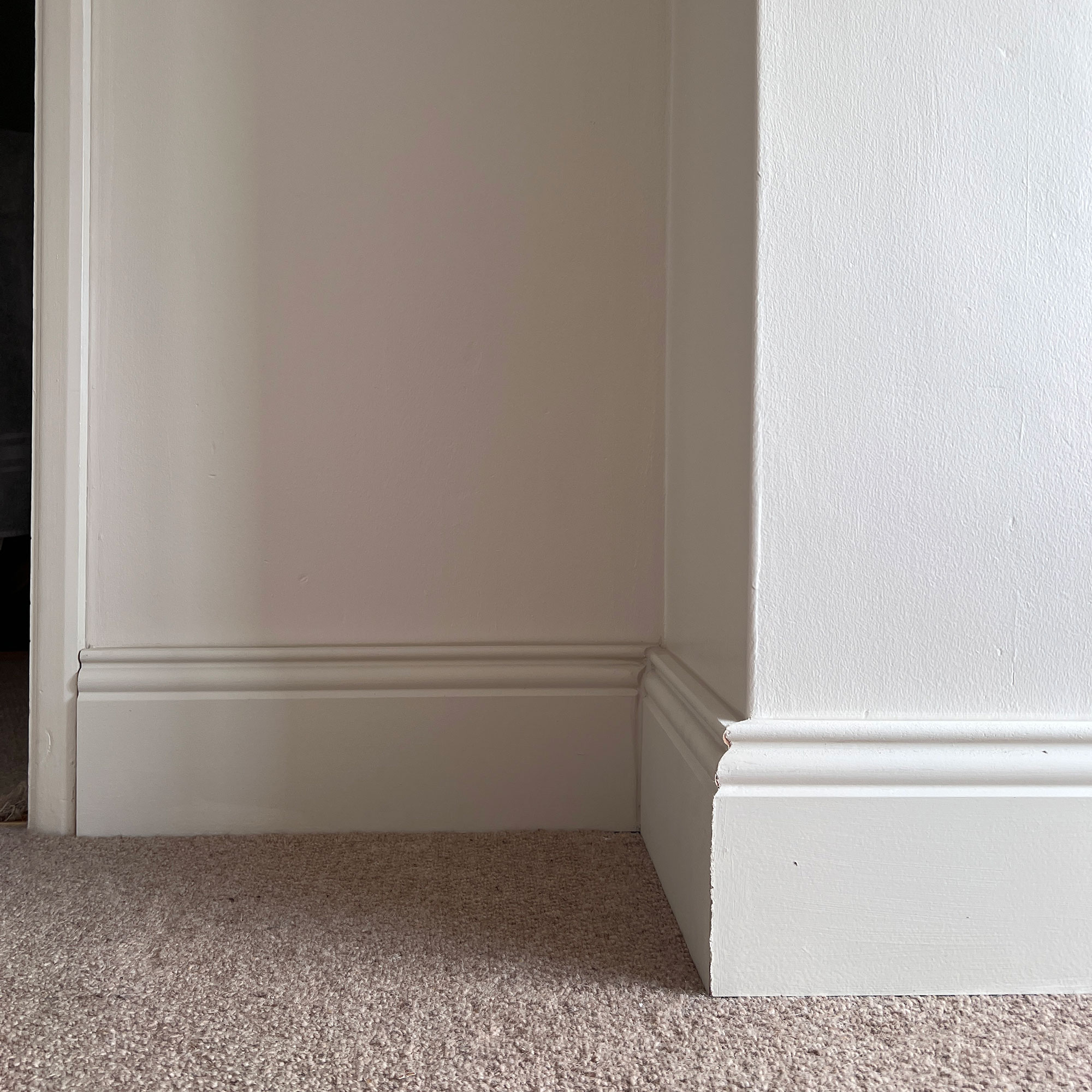 White wall with skirting board by neutral carpet