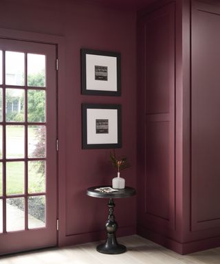 entryway color-drenched in dark purple paint with two framed prints and black side table