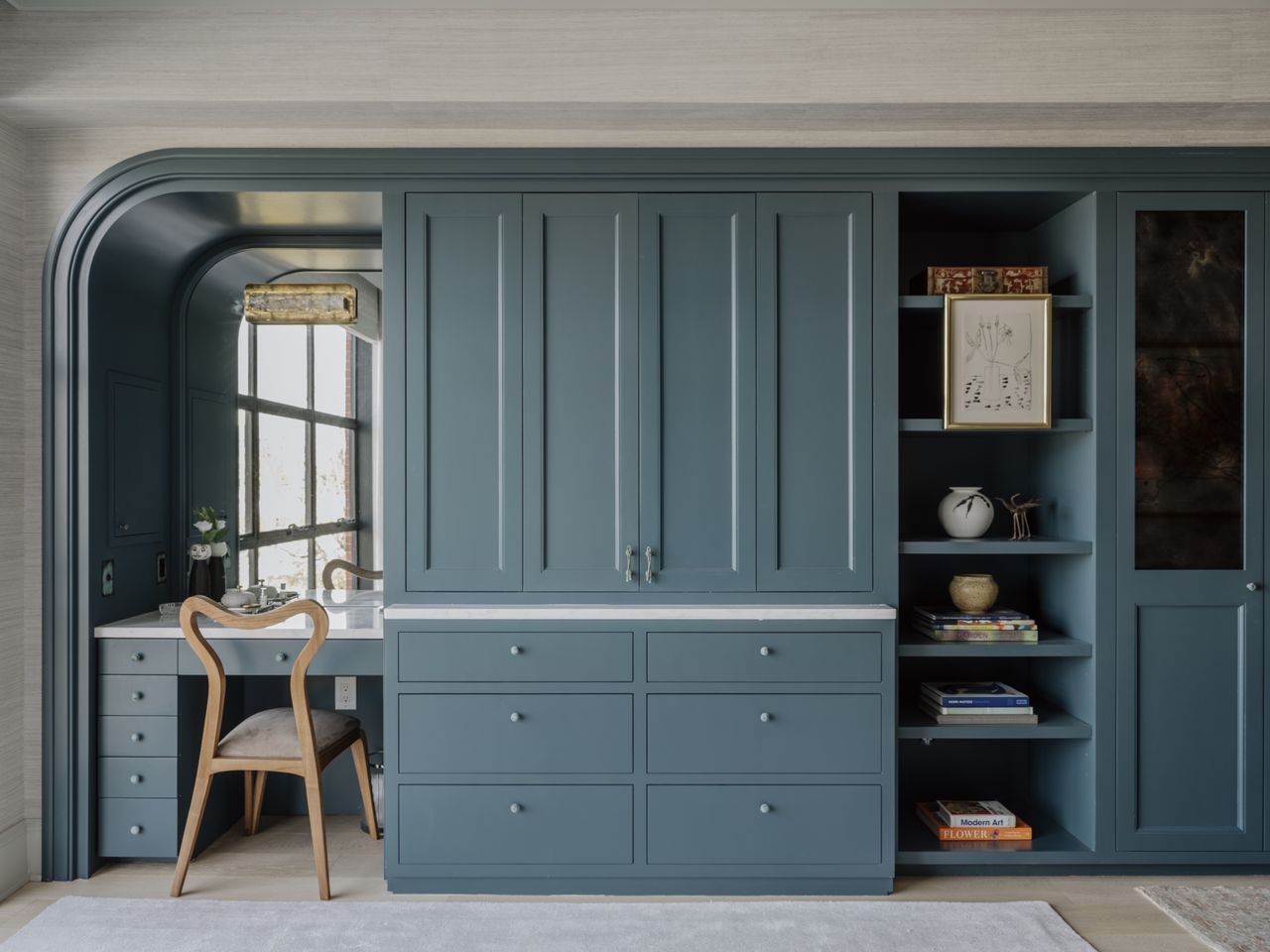 A bedroom with a blue integrated closet and vanity