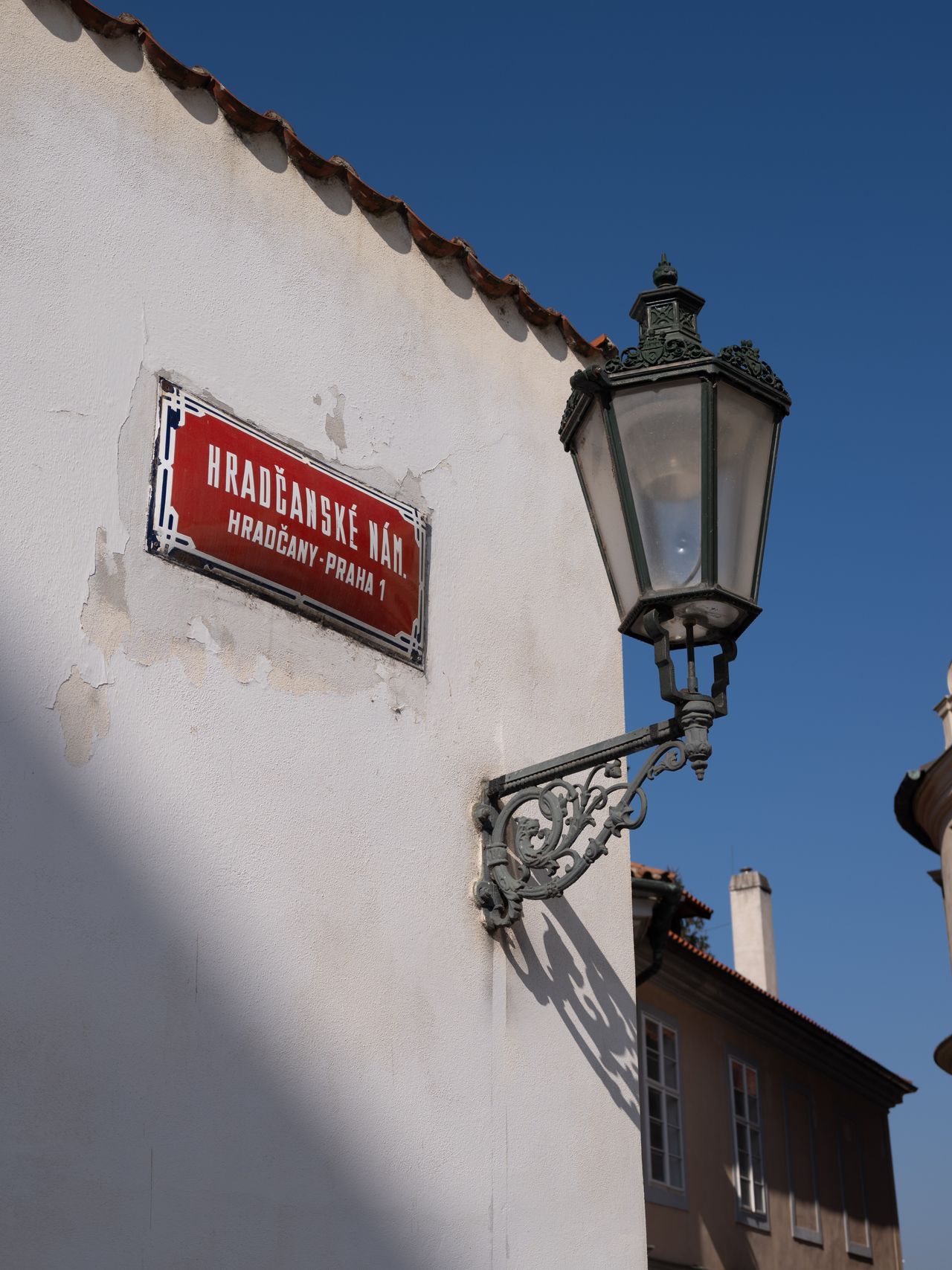 A street sign in Prague next to an old street light