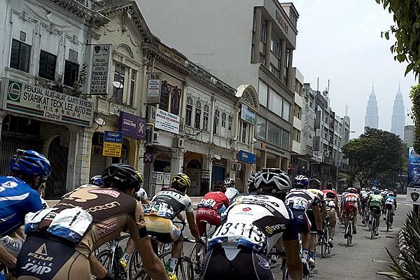 The peloton head into Kuala Lumpur with KLCC towers in the background.