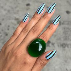 a woman with blue and black striped nails and a green ring