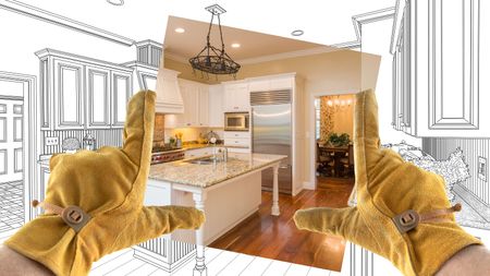 Male contractor hands framing a photo of a kitchen update over sketches 