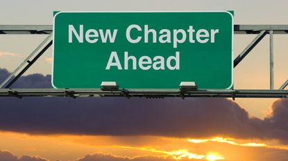 A road sign says "New Chapter Ahead," set against a pretty sunset.