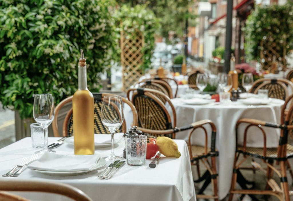 an image of the outdoor terrace at le petite maison with a table laid ready for service