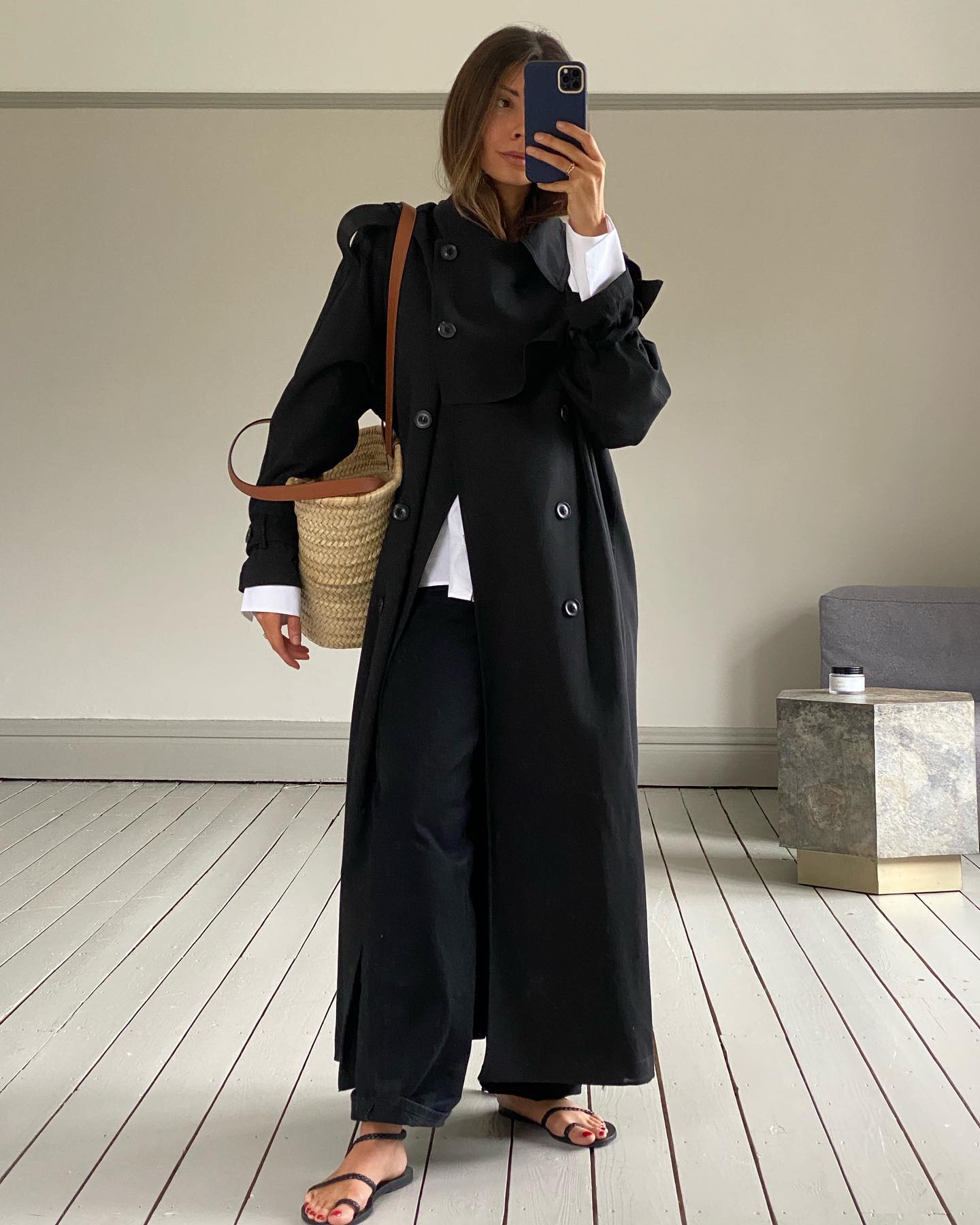 @smythsisters wears a pair of sandals with asymmetric straps with a some black trousers and a trench coat