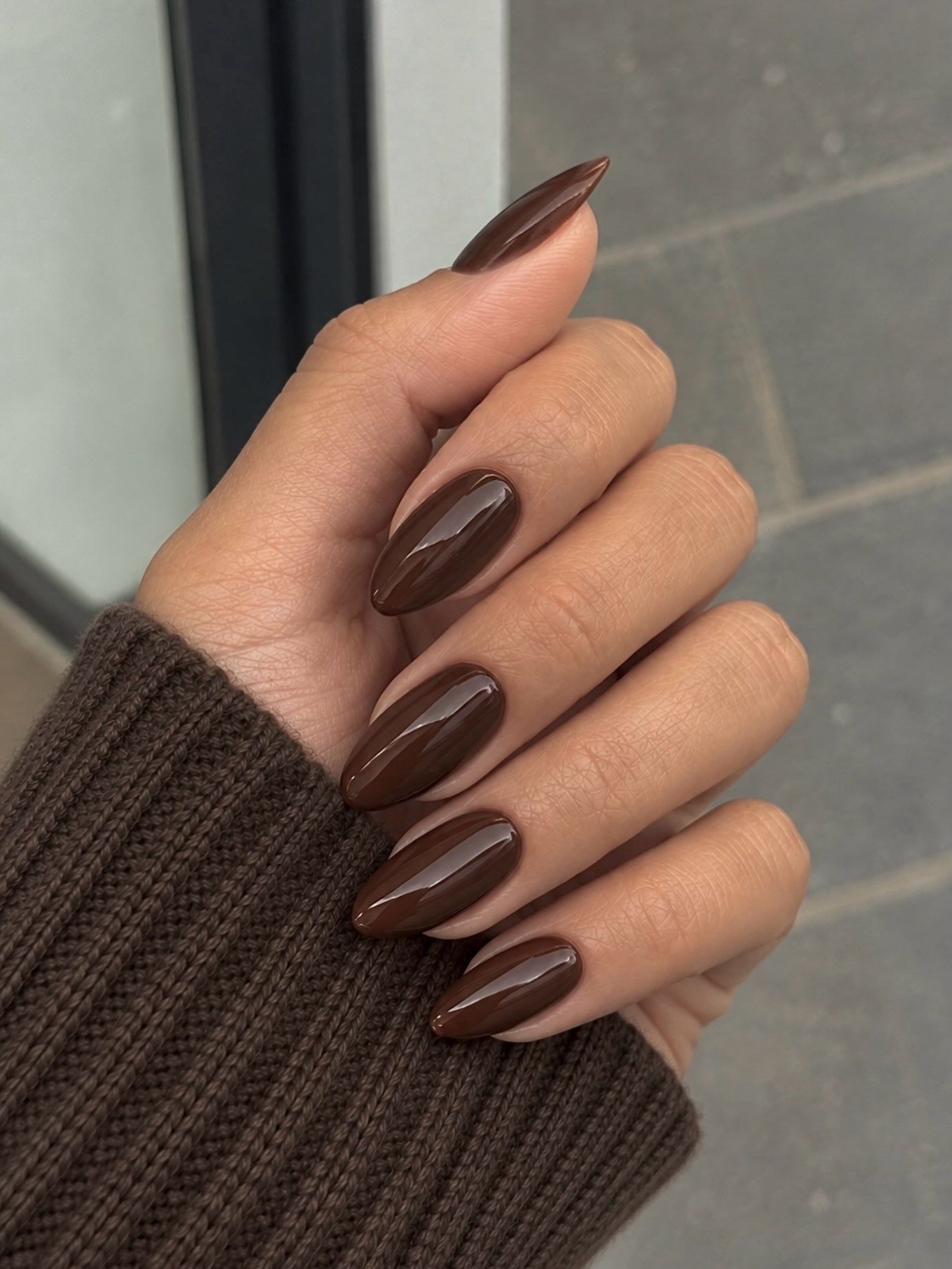 long almond nails in a rich glossy espresso shade, paired with a brown knit sleeve