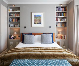 A bedroom with inset storage shelves behind headboard
