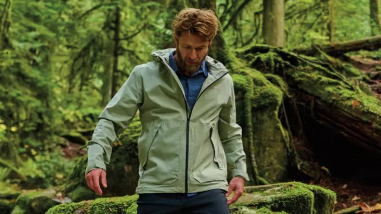 A hiker in the forest wearing the Columbia Altbound Jacket