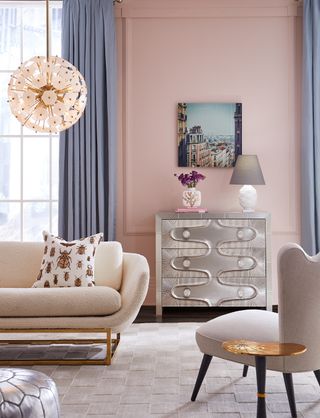 pink living room with pale blue drapes, art deco style furniture, metallics, boucle couch, silver chest of drawers, pendant light, rug, armchair, silver foot stool