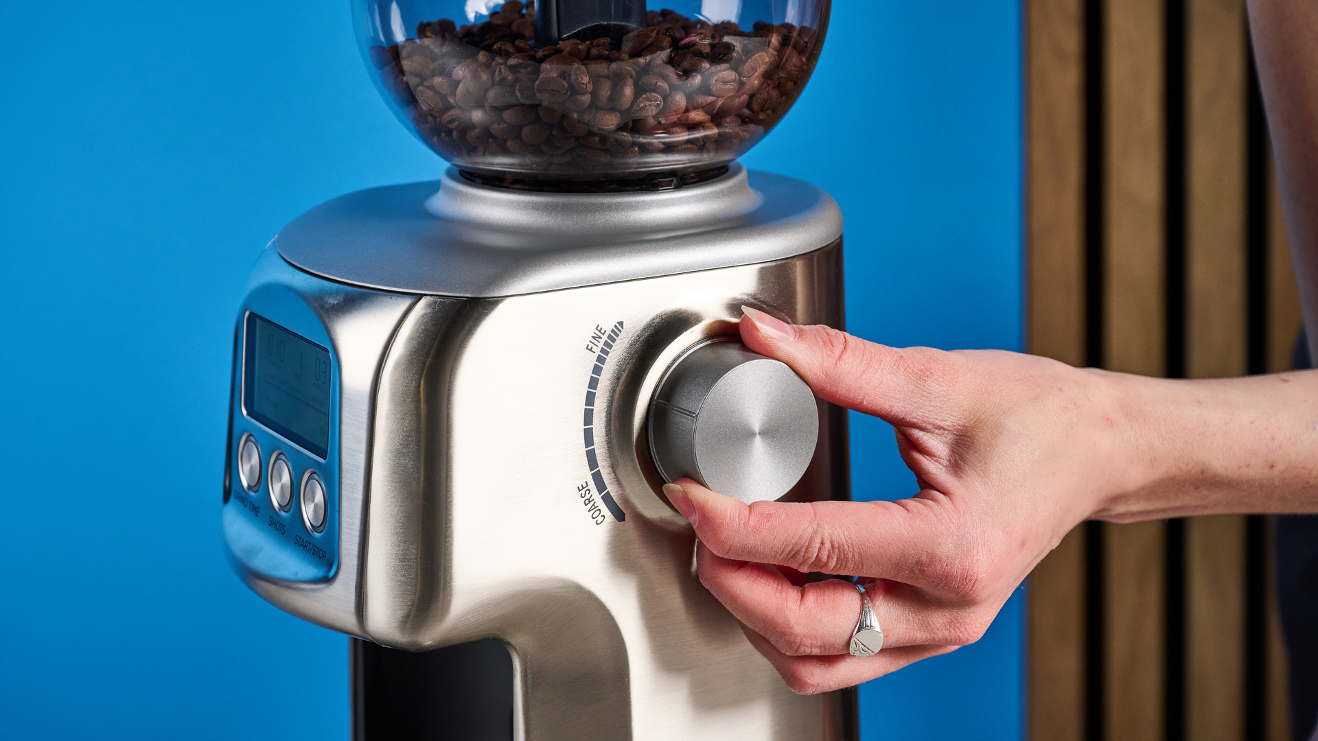 the casabrews tornado coffee grinder in silver showing the LED screen, grind adjustment dial, and photographed against a blue background